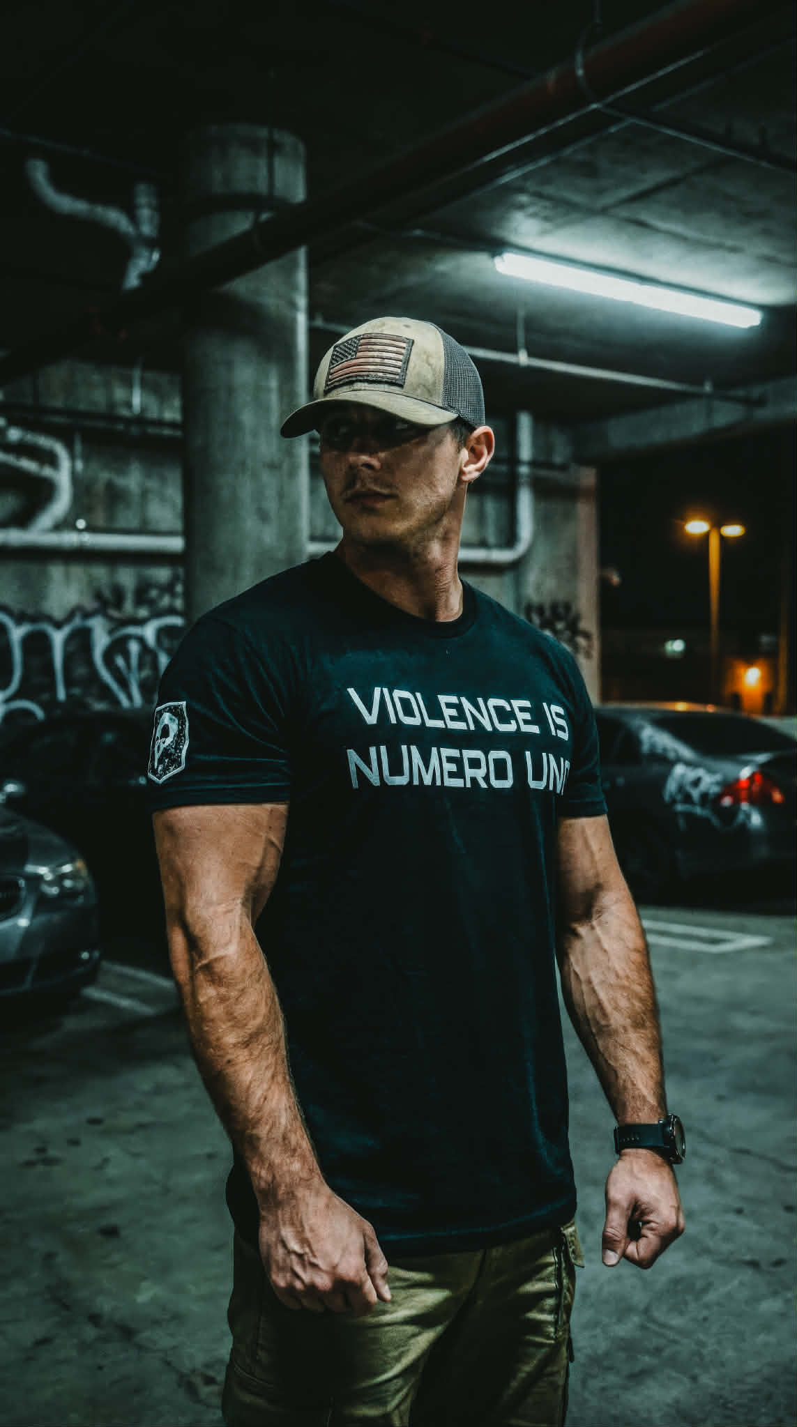 Man wearing a black t-shirt with 'Violence is Numero Uno' text in an urban setting.